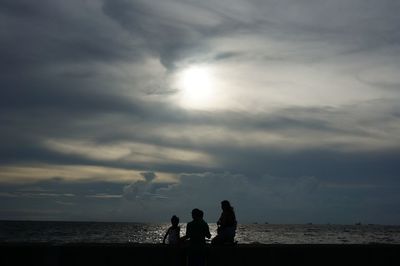 Silhouette of couple sitting on beach