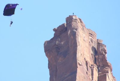 Low angle view of person paragliding against clear blue sky