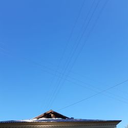 Low angle view of electricity pylon against clear blue sky