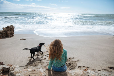 Woman with dog at beach against sky