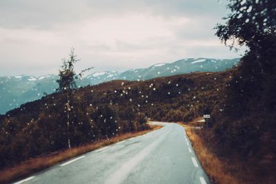 Road by mountains against sky during winter