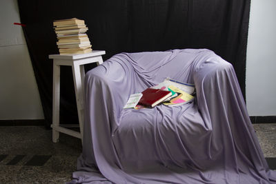 Rear view of man reading book on bed at home