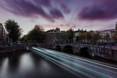 Bridge over river in city against sky