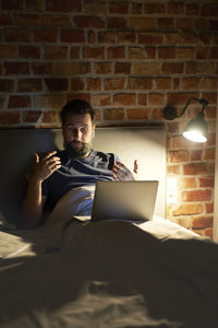Businessman using laptop on bed at night