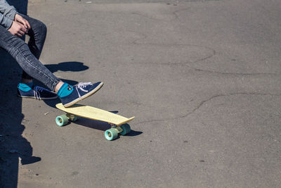 Low section of woman skateboarding on road