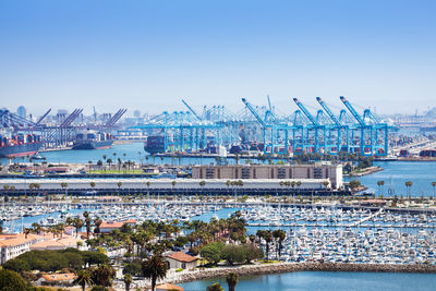 Cranes at harbor against clear sky