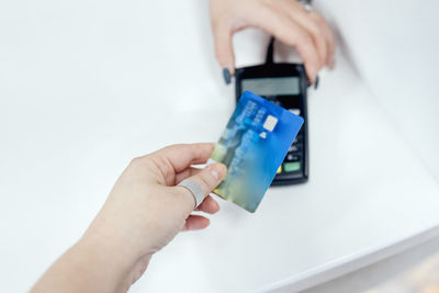 Cropped hands of person holding credit card against white background