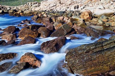 High angle view of stream amidst rocks in sea