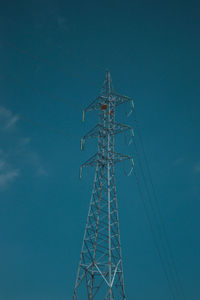 Low angle view of electricity pylon against blue sky