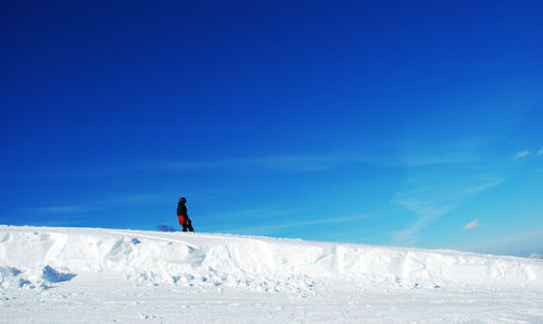 One person walking on snowy area against clear sky