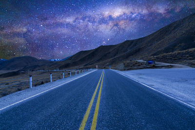 Road amidst mountains against sky at night