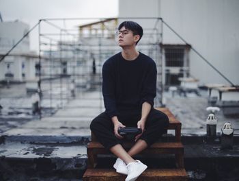 Full length of young man sitting outdoors