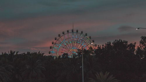 Illuminated ferris wheel against sky at dusk