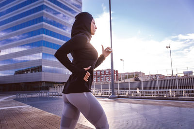 Side view of man standing against sky in city