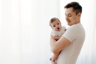 Happy father with baby in arms at home
