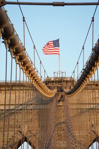 Low angle view of flags on bridge against sky