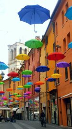 Multi colored umbrellas in city against sky