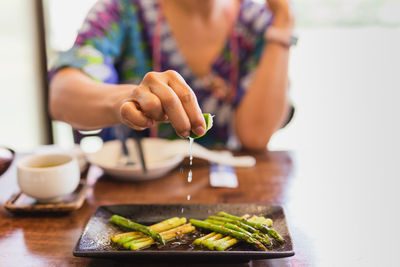 Female hand squeezing lime on cooked asparagus