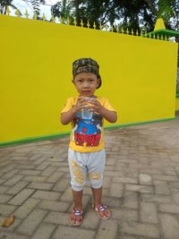 Portrait of boy standing against yellow wall