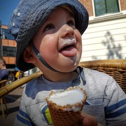 Boy looking away while eating ice cream at sidewalk cafe