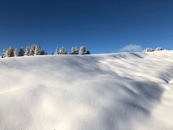 Low angle view of snow covered landscape against blue sky