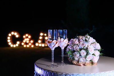 Champagne flutes and bouquet on table at night