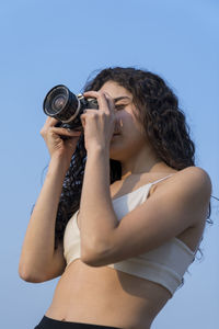 Woman photographing against sky