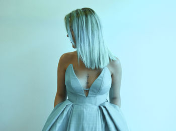 Young woman standing against white wall