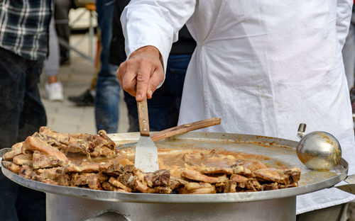 Midsection of chef preparing meat dish in large pot with plate. traditional croatian dish kotlovina