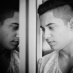 Close-up of young man looking through window