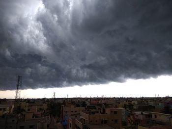 Houses in city against storm clouds