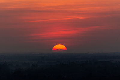 Silhouette landscape against orange sky