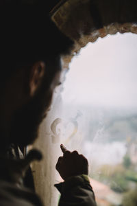 Man drawing with his finger a heart in wet window