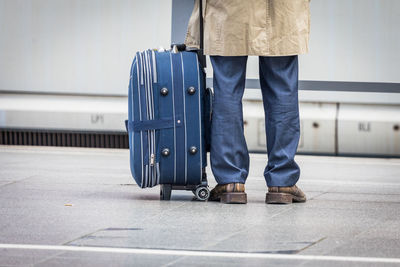 Low section of man standing with luggage on tiled floor