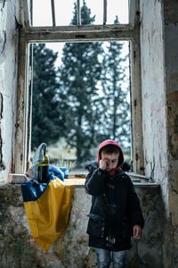 Portrait of young woman standing by window