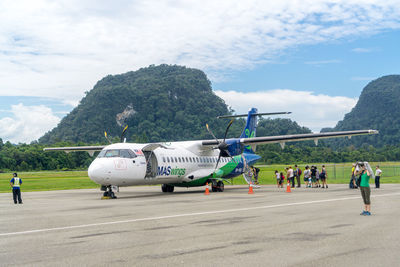 People at airport runway against sky