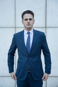 Portrait of young man standing against wall