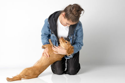 Young woman with dog sitting against white background