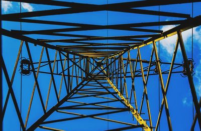 Low angle view of electricity pylon against blue sky