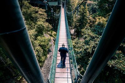 Rear view of man walking on footbridge