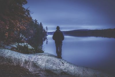 Rear view of man looking at lake against sky