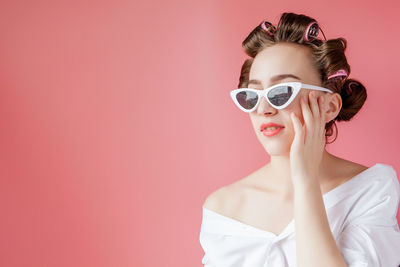 Portrait of young woman wearing sunglasses against gray background
