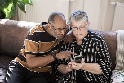 Senior couple using smart phone in living room