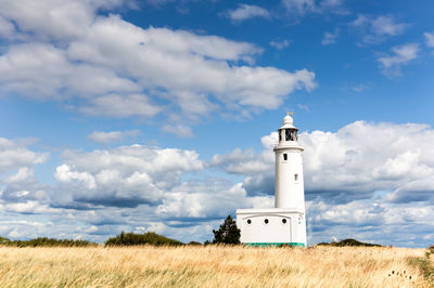 Lighthouse on field against sky