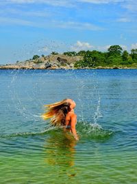 Side view of young woman tossing hair in sea
