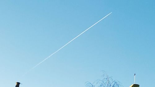 Low angle view of vapor trails against blue sky