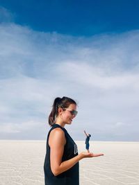 Side view of young woman on beach against sky