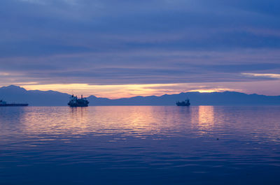 Silhouette boat sailing on sea against sky at sunset