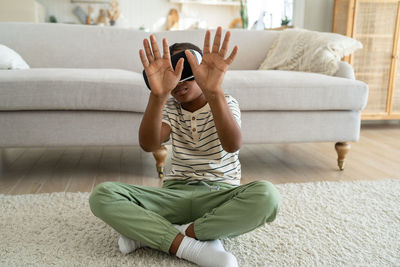 Young woman using mobile phone while sitting on sofa at home