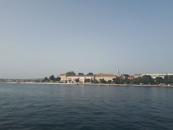 Scenic view of sea by buildings against clear sky